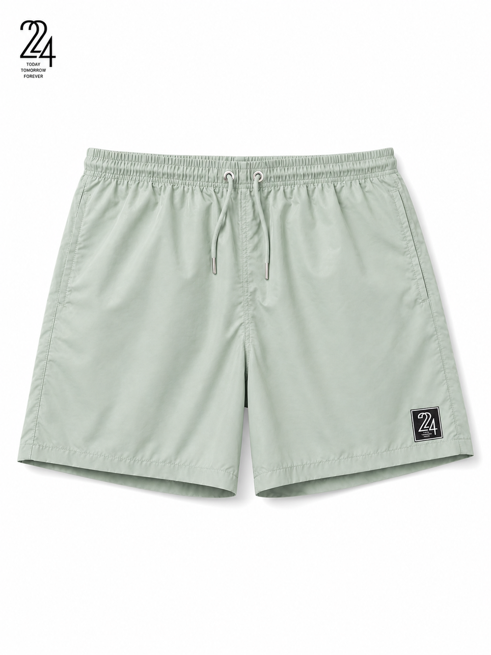 A pair of sage green athletic shorts with an elastic waistband, drawstring, and a small black '24' brand patch on the lower left leg, shown against a plain white background.